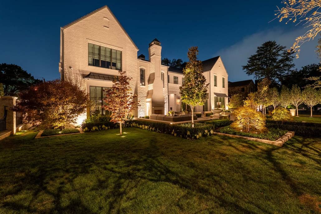 Elegant Residential Outdoor Lighting Design Beautifully illuminated house with landscape lighting highlighting trees and garden features at night.