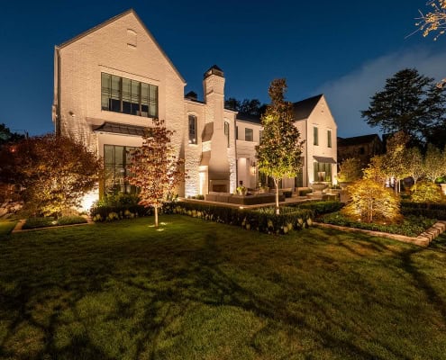 Elegant Residential Outdoor Lighting Design Beautifully illuminated house with landscape lighting highlighting trees and garden features at night.