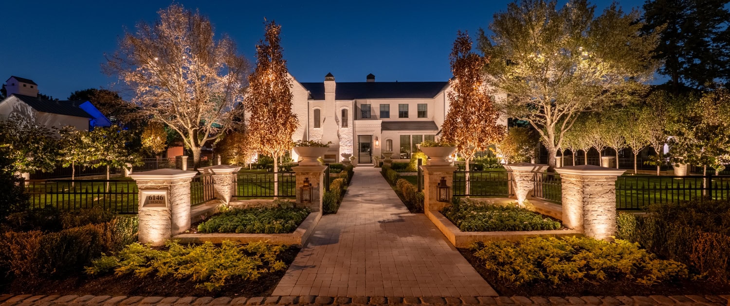 Elegant Mansion with Landscape Lighting Night view of a luxurious mansion illuminated by outdoor landscape lighting, highlighting trees, pathways, and architectural features for enhanced curb appeal.