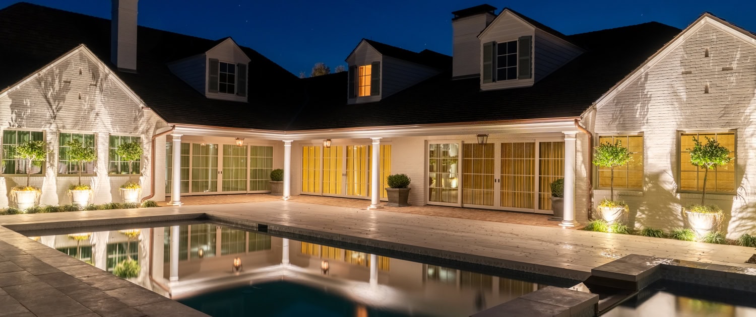 Elegant Backyard with Pool and Outdoor Lighting Luxury backyard at night featuring a well-lit swimming pool, outdoor lighting, and a modern house with large windows and a patio area.