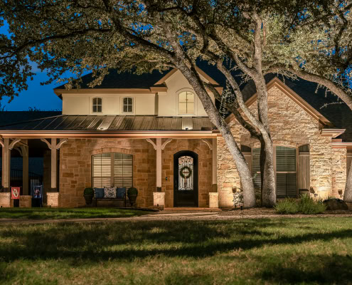 Elegant residential house illuminated by outdoor lighting at dusk, showcasing landscape and architectural features.
