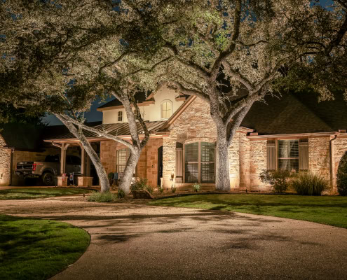 Elegant residential house illuminated by outdoor lighting at night, showcasing landscape and architectural features.