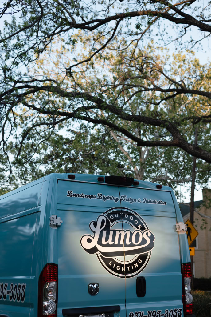 Lumos Outdoor Lighting Service Vehicle Lumos outdoor lighting service van parked under trees, showcasing landscape lighting design and installation services.