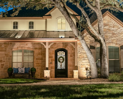 Beautiful residential home illuminated by outdoor lighting, showcasing landscape and architectural features at night.