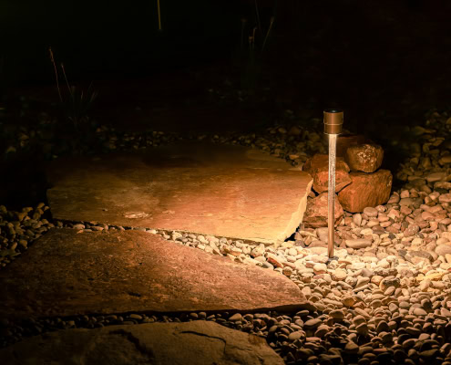Landscape pathway illuminated by Lumos outdoor lighting, showcasing a stone walkway with soft, warm LED lights for enhanced safety and aesthetic appeal.