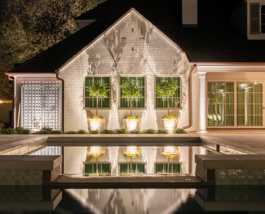 Outdoor Lighting for Home Exterior Elegant outdoor lighting illuminating the exterior of a house at night, highlighting the landscaping and pool area.
