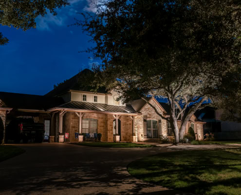 Residential house exterior illuminated by Lumos outdoor lighting at night, showcasing landscape and pathway lighting for enhanced curb appeal.